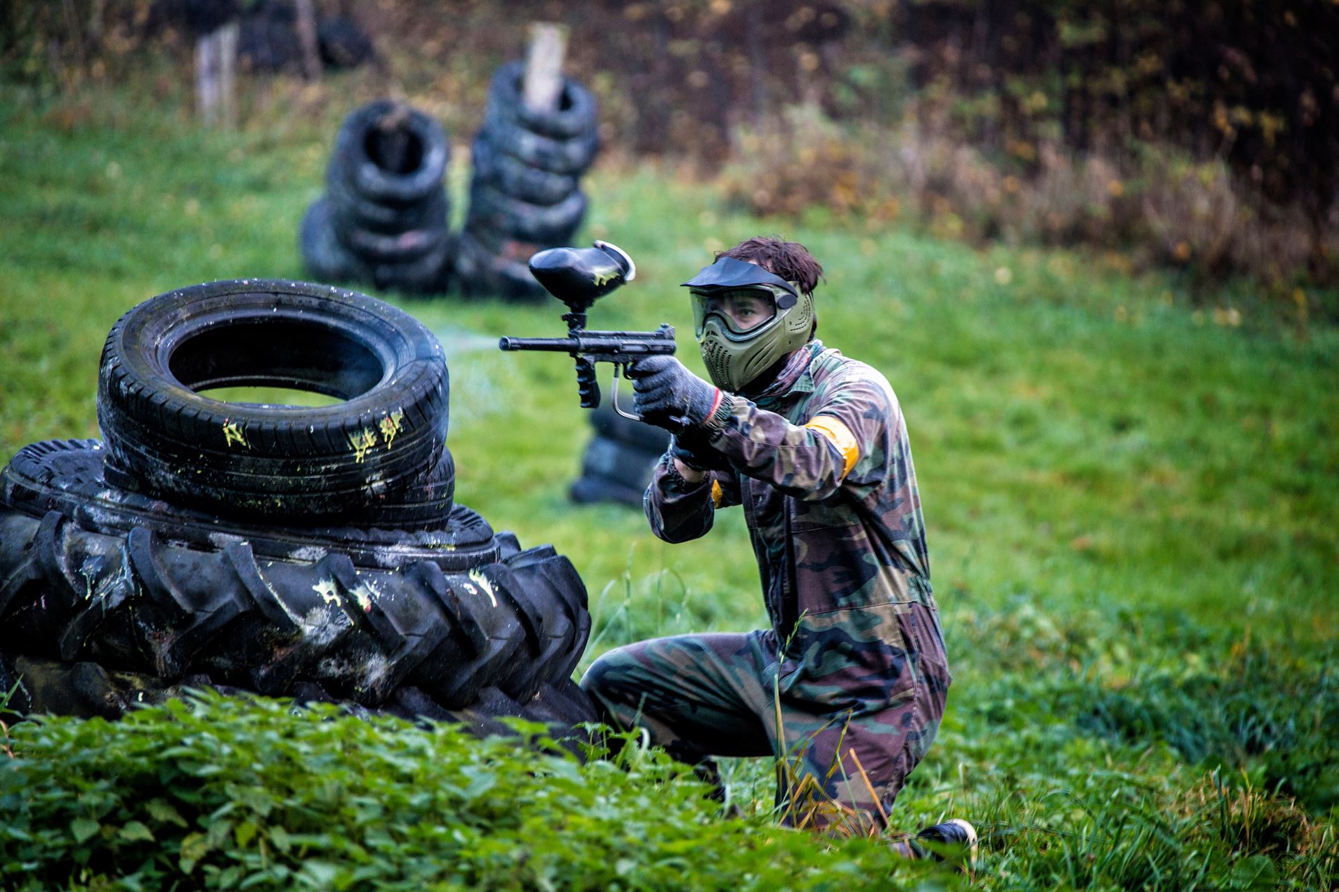 mężczyzna strzelający z paintball, ubrany w kombinezon wojskowy